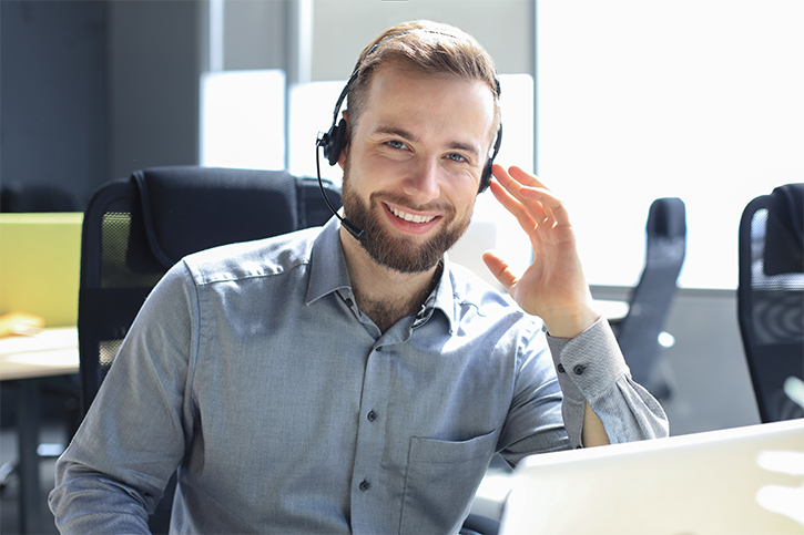Smiling call center associate in light blue shirt speaking into his headset